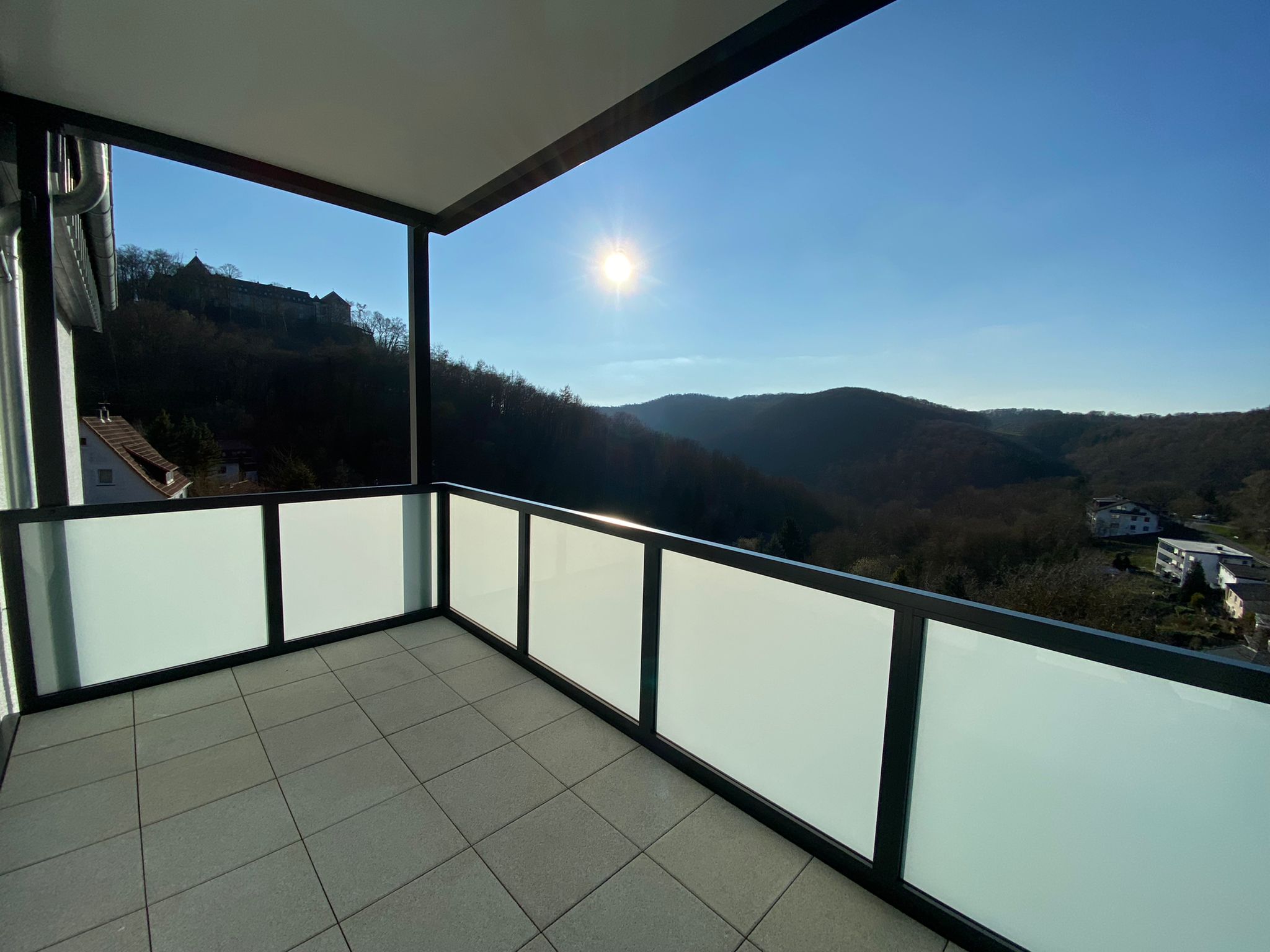 Blick vom Balkon auf die Berge, blauer Himmel, am Horizont die Sonne